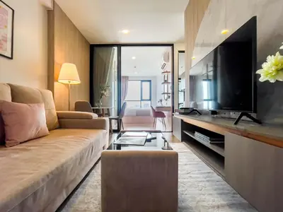a living room with a couch and a flat screen tv at Near BTS Bearing l Rooftop pool and gym in Bangkok