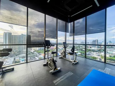 a gym with a view of a city at Near BTS Bearing l Rooftop pool and gym in Bangkok