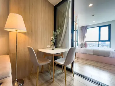 a room with a table and chairs and a bed at Near BTS Bearing l Rooftop pool and gym in Bangkok