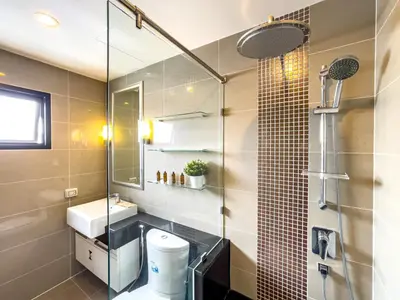 a bathroom with a toilet and a glass shower at Near BTS l Large 85 sqm l Rooftop Pool l Sontana in Bangkok