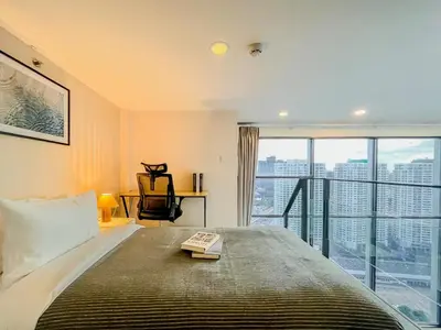 a bedroom with a bed and a large window at Duplex near BTS l Rooftop Pool l Skyline l Sontana in Bangkok