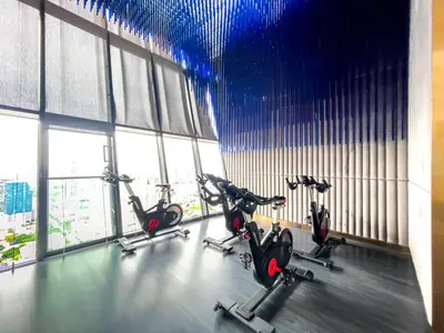 a gym with several cardio bikes in a room with windows at Near BTS l Fully Furnished l Pool and Gym l Sontana in Bangkok