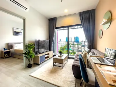 a living room with a couch and a desk with a laptop at Near BTS l Fully Furnished l Pool and Gym l Sontana in Bangkok