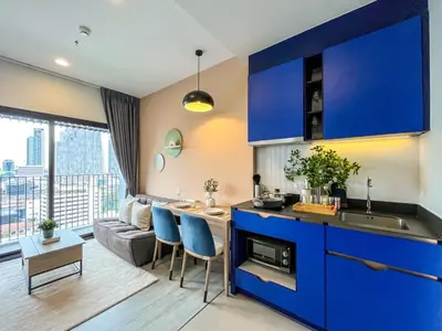 a kitchen with blue cabinets and a living room at Near BTS l Fully Furnished l Pool and Gym l Sontana in Bangkok