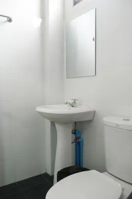 a white bathroom with a sink and a toilet at Baan Mai Guest House in Bangkok