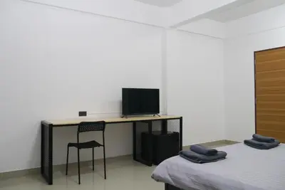 a room with two beds and a desk with a television at Baan Mai Guest House in Bangkok