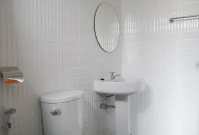 a bathroom with a sink and a toilet and a mirror at Baan Mai Guest House in Bangkok