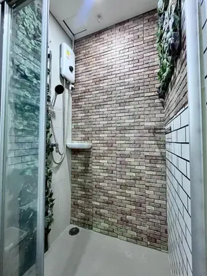 a bathroom with a shower with a brick wall at Na casa da minha amiga in Bangkok