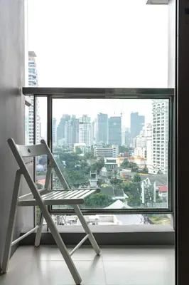 a chair in front of a window with a view of a city at Free Airport Pick Up Rooftop Pool Gym near BTS Emquartier Shopping city center in Bangkok