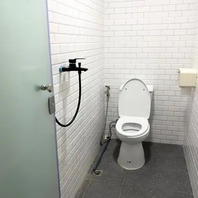 a white bathroom with a toilet in a stall at Box me in Bangkok