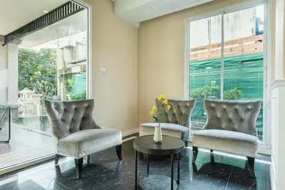 a living room with chairs and a table and a window at ZAYN Bangna Hotel in Bangna