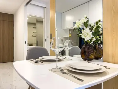 a table with plates and glasses and a vase of flowers at BTS Thong Lol Large 52 sqm l Pool and Gym l Sontana in Bangkok