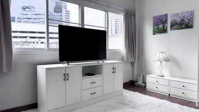 a living room with a flat screen tv on a white cabinet at Blissful Heaven Residence at BTS Phromphong Emdistrict Shopping Area in Bangkok