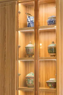 a wooden cabinet filled with blue and green pottery at TUAN Hotel Bangkok in Bangkok Yai