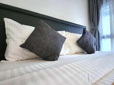 a bed with three pillows on top of it at Prime 1BR in Sukhumvit 11 CentralStylishModern in Makkasan