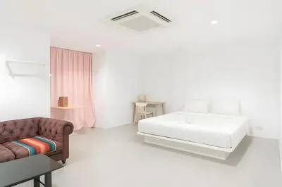 a white bedroom with a bed and a couch at XX Mitr Inn Sukhumvit 2 - มิตร อินน์ สุขุมวิท 2 in Bang Kapi