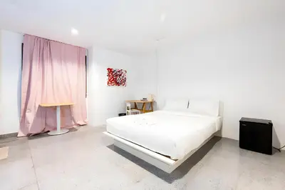 a bedroom with a white bed and a pink curtain at XX Mitr Inn Sukhumvit 2 - มิตร อินน์ สุขุมวิท 2 in Bang Kapi