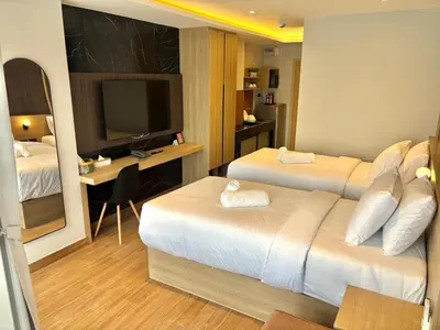 a hotel room with two beds and a desk and a television at J5 Hotel in Ban Zong Katiam