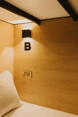 a bedroom with a wooden wall with the letter b on it at City Pause Hostel in Sathani Bang Su