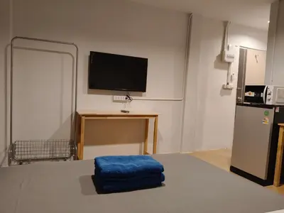 a room with a television and a blue pillow on a table at D45 Home - BTS Ratchathewi N1 Station in Bangkok