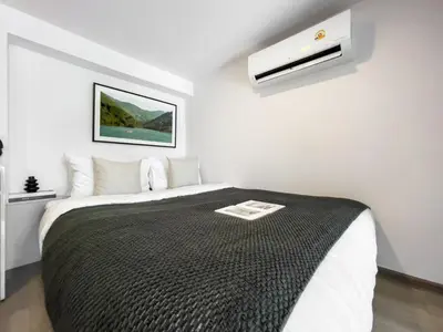 a bedroom with a bed with a black blanket at 250m BTS l Duplex Unit l Rooftop Pool l Sontana in Bangkok