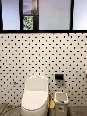 a bathroom with a toilet and a black and white tiled wall at Pridi cozy home with good location Type C in Bangkok