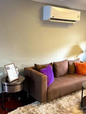 a living room with a brown couch with colorful pillows at Pridi cozy home with good location Type C in Bangkok