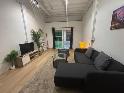 a living room with a black couch and a tv at Siam Central 2BR Yumi house Near IconSiam in Bangkok