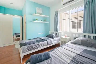two beds in a room with blue walls and a mirror at Modern 3BR Rama Mansion Near Airport plus Amenities in Sathani Ban Hua Mak