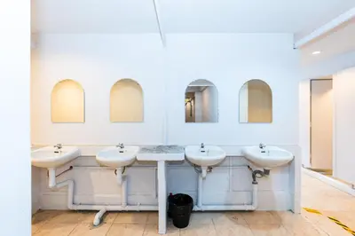 a bathroom with three sinks and two mirrors at The Hidden Khaosan Bangkok in Bang Bua Thong Railway Station