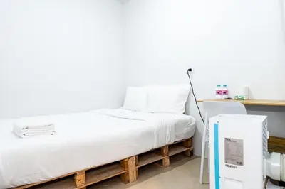 a bed in a room next to a refrigerator at The Hidden Khaosan Bangkok in Bang Bua Thong Railway Station