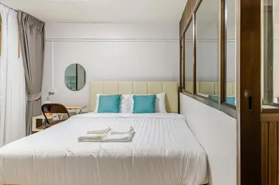 a bedroom with a large white bed with blue pillows at Cozy 5-story house, 2 mins walk BTS, BKK in Bangkok