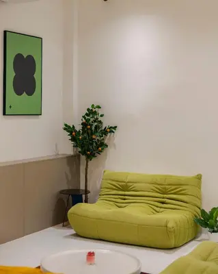 a green couch in a room with a plant at Bembis Hotel Charoenakorn 10 in Chinatown