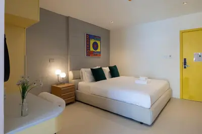 a bedroom with a large white bed and a table at Bembis Hotel Charoenakorn 10 in Chinatown
