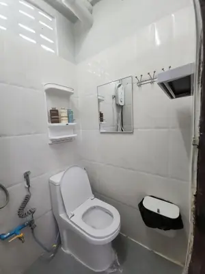 a bathroom with a toilet and a phone on the wall at Sabai room in Taling Chan