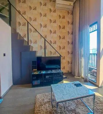 a living room with a table and a staircase at Luxury duplex condominium Samyan area 28th fl near MRT in Bangkok