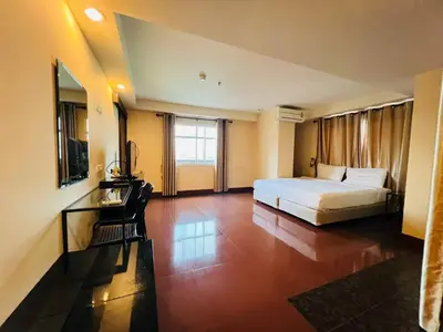 a bedroom with a bed and a desk and a television at NSC Apartel in Bangkok