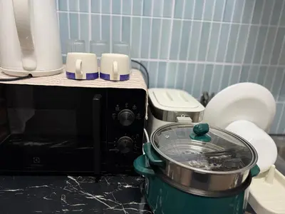 a slow cooker sitting next to a microwave at Bongo Residence Ratchathewi Bangkok in Bangkok