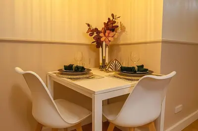 a white table with chairs and a vase with flowers at Cozy Designer Apartment - Sukhumvit 39 in Bangkok