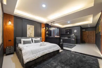 a bedroom with a large bed and a kitchen at Delta 9 Phrakanong in Bangkok