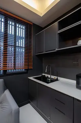a kitchen with black cabinets and a sink at Delta 9 Phrakanong in Bangkok