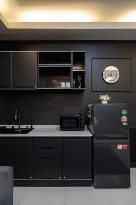 a black kitchen with a refrigerator and a microwave at Delta 9 Phrakanong in Bangkok