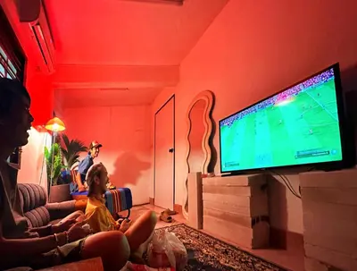 a family sitting in a living room watching a television at Super BIG Mid Century Home near River & IconSiam in Khlong San