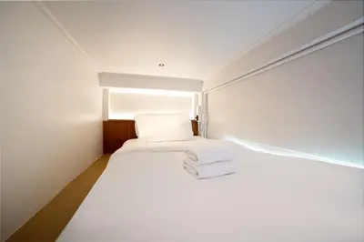 a bedroom with a white bed with a window at OH Suites 72 in Bangkok