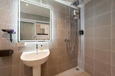 a bathroom with a sink and a shower with a mirror at OH Suites 72 in Bangkok