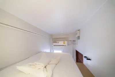 a bedroom with a white bed with white pillows at OH Suites 72 in Bangkok