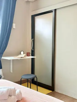 a bedroom with a sliding glass door with a stool next to a bed at Office 3 in Bangkok