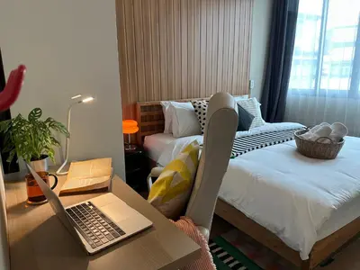 a bedroom with a desk with a laptop on a bed at Office 3 in Bangkok