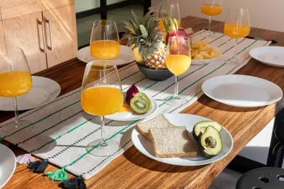 a table with glasses of orange juice and bread and fruit at Walk2BTS, KingBed, FastWiFi, FreeLaundry, Netflix in Khlong Toei