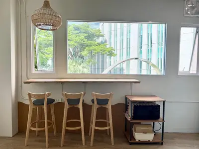 a kitchen with three bar stools and a counter with a window at Nana Best Hostel in Makkasan